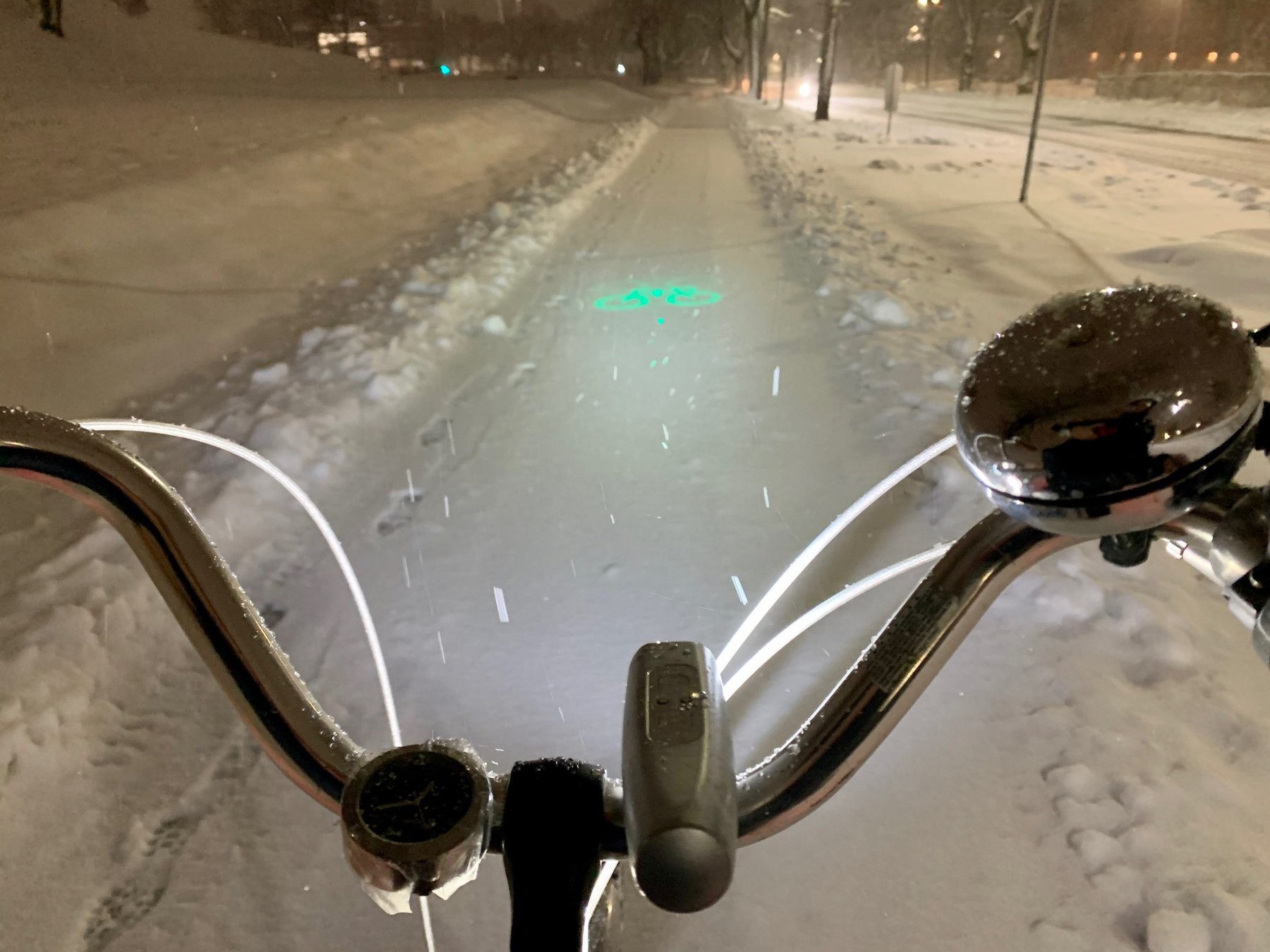 A snow-covered pathway framed by bicycle handlebars