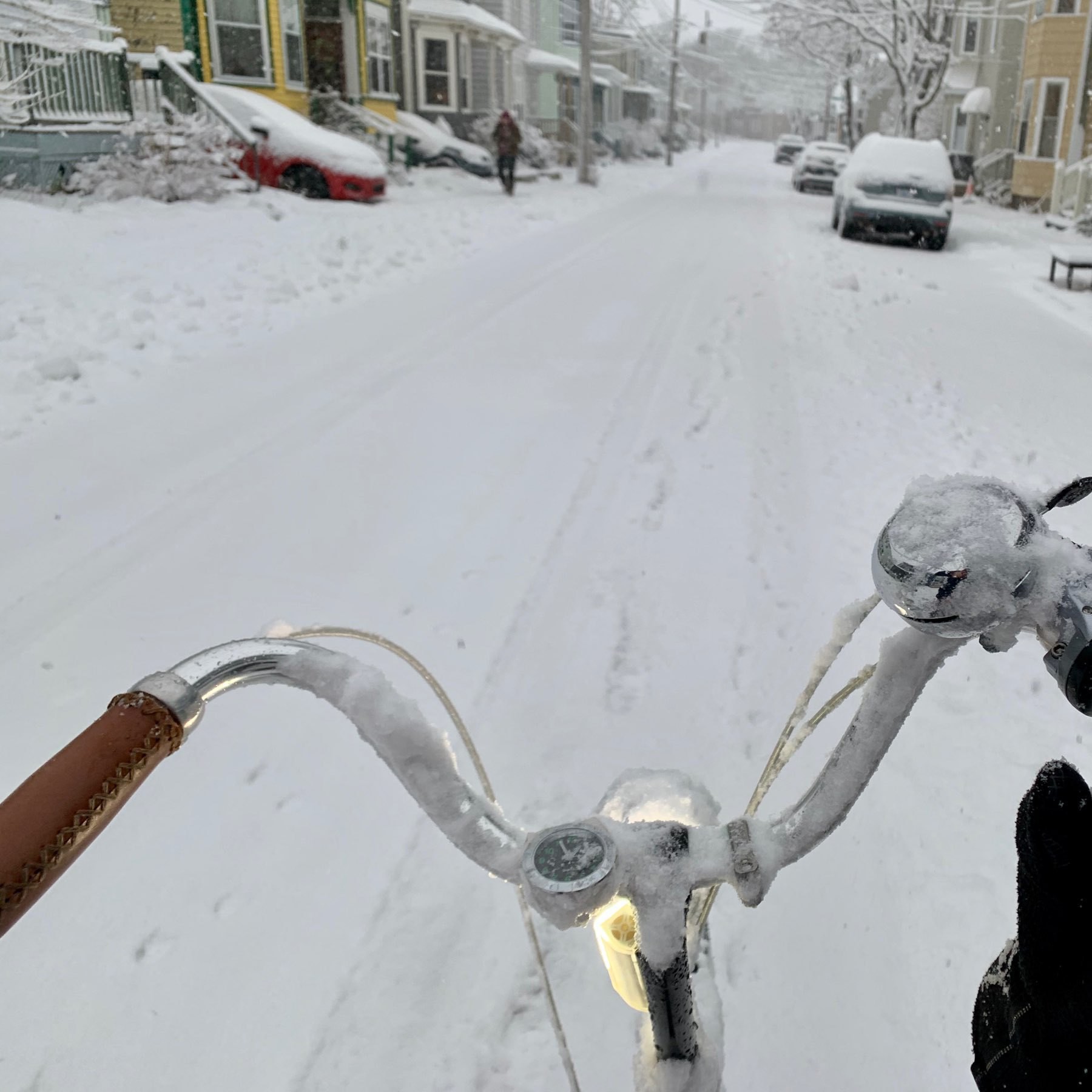 View of a snowy sidestreet from a bicycle-rider's perpective